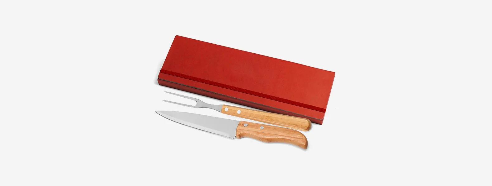 Conjunto composto por uma faca 7” e um garfo trinchante, ambos com cabos em bambu e lâminas em aço Inox com rebites resistentes. Estão organizados em uma pasta vermelha com elásticos.
