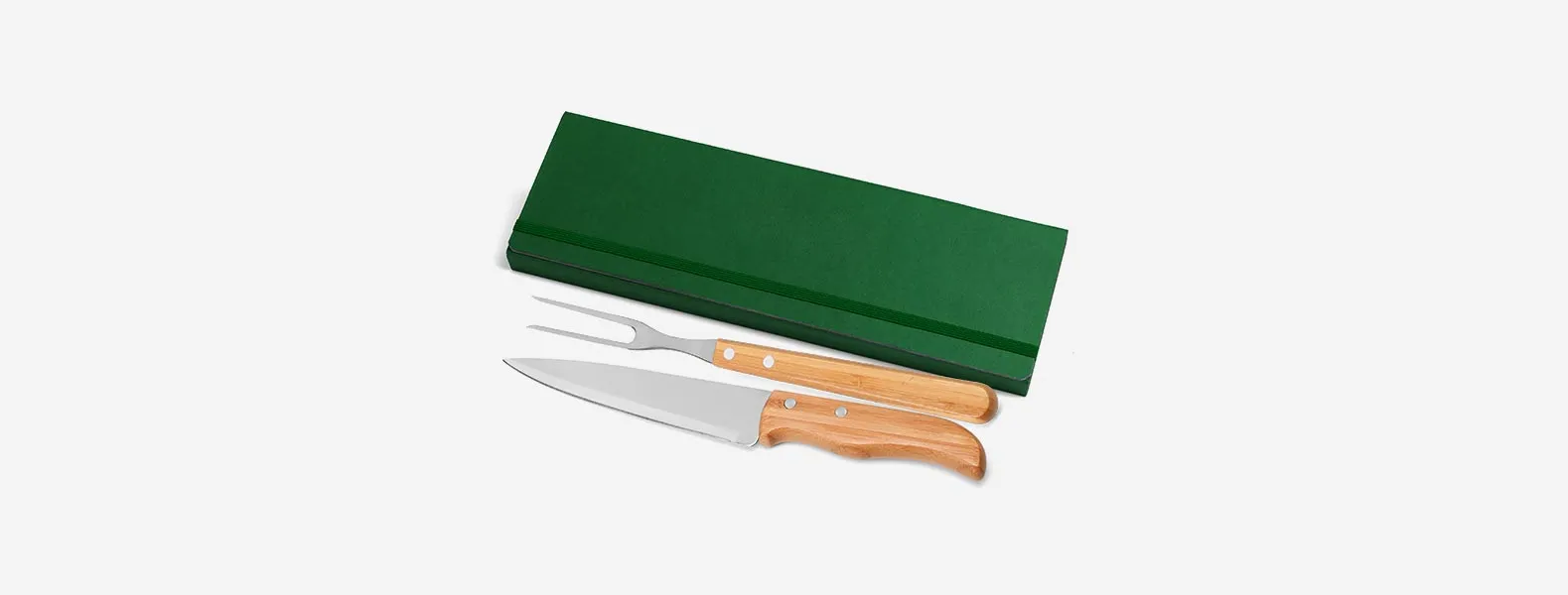 Conjunto composto por uma faca 7” e um garfo trinchante, ambos com cabos em bambu e lâminas em aço Inox com rebites resistentes. Estão organizados em uma pasta verde com elásticos.