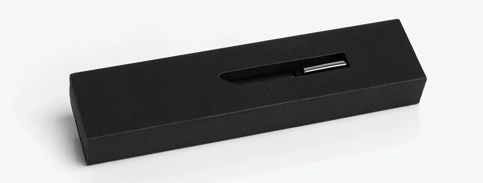 Caneta esferográfica em metal preta. Conta com carga esferográfica azul acionada por um giro no corpo da caneta; clip cromado; caixa para presente.