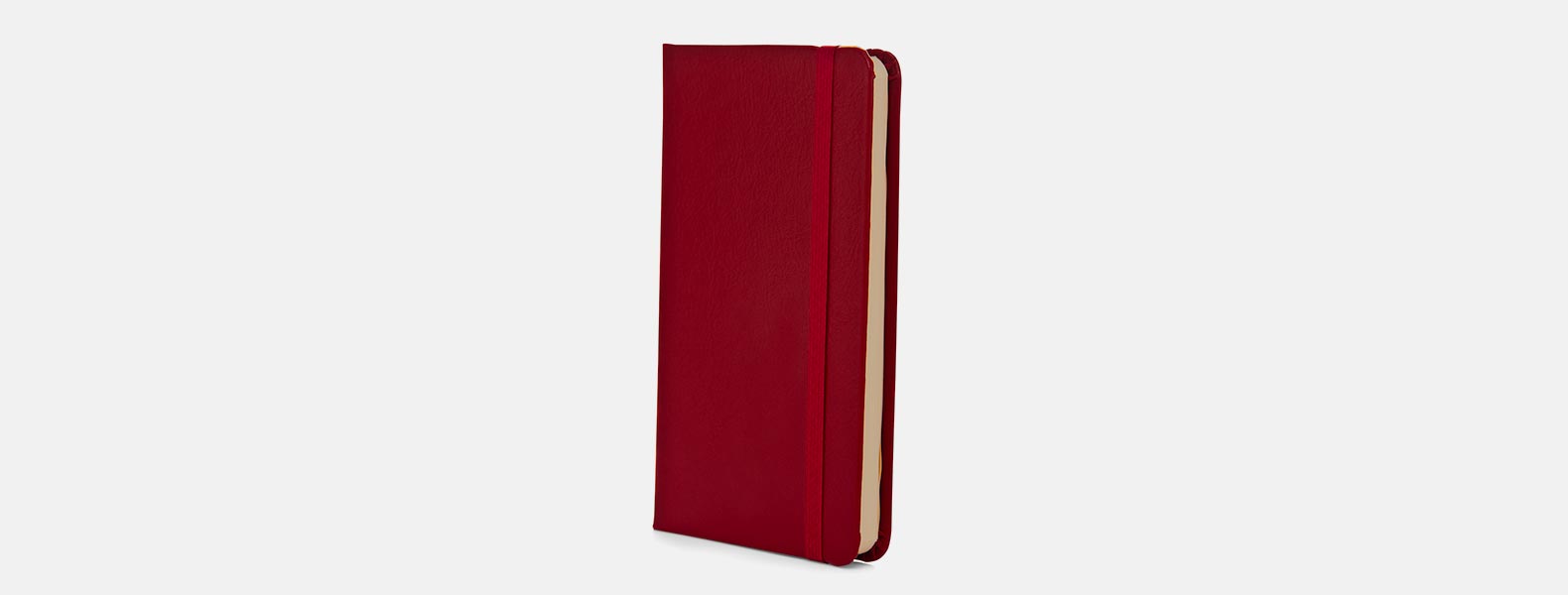 Caderno para anotações vermelho com capa dura em Courino. Conta com 80 folhas não pautadas e elástico para fechamento. Gramatura da folha de 70 g/m2.