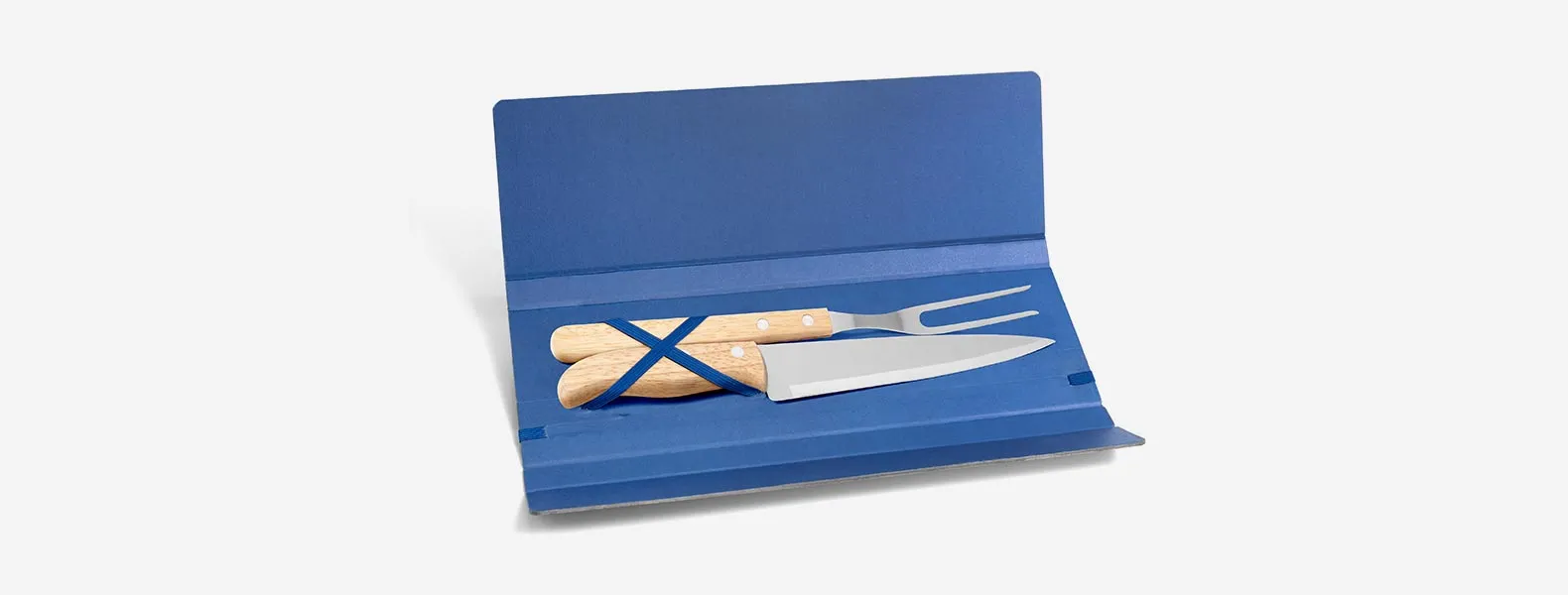 Conjunto composto por uma faca 7” e um garfo trinchante, ambos com cabos em madeira e lâminas em aço Inox. Estão organizados em uma pasta azul com elásticos.