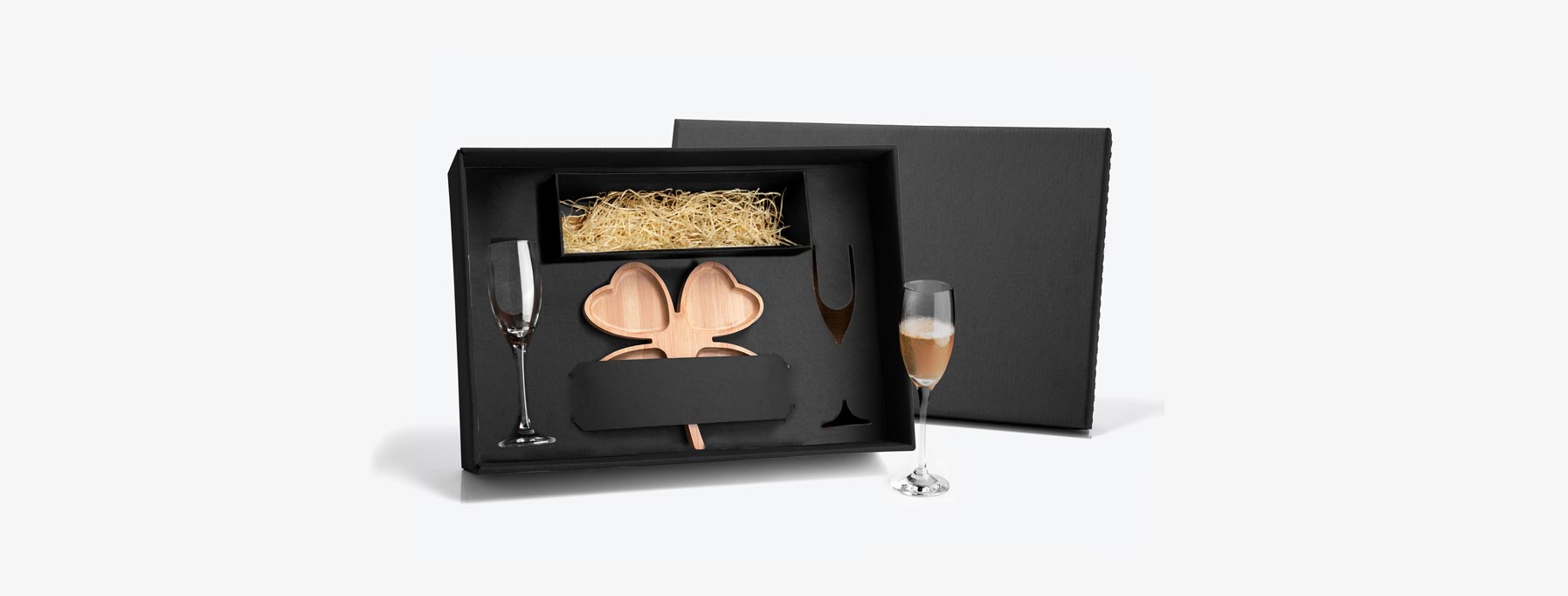 Kit para Petisco e Champagne; Conta com petisqueira formato de trevo em Bambu; Duas taças para champagne em vidro; Espaço para garrafa com palha (NÃO ACOMPANHA GARRAFA). Estão perfeitamente acomodados em uma caixa para presentear.