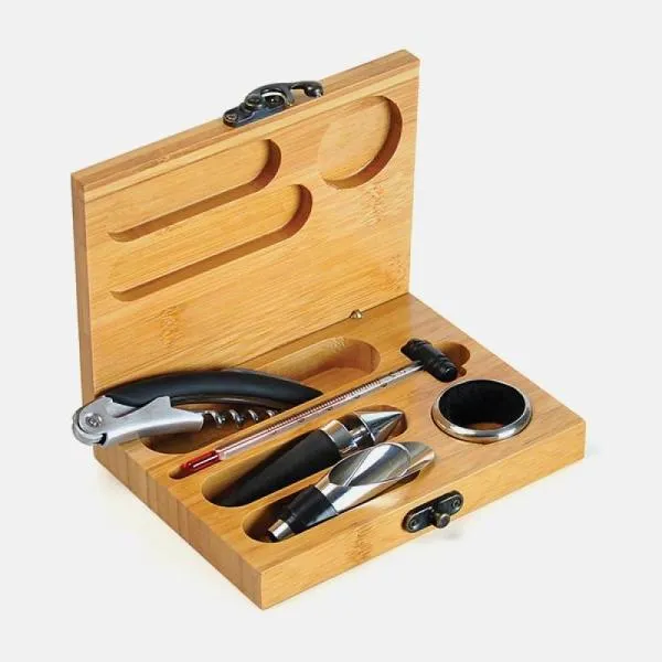 Kit para vinho. Composto por cinco acessórios para vinho em metal e inox, sendo um anel corta-gotas, um funil direcionador com tampa e tampão, ambos com detalhes emborrachados para melhor fixação na garrafa, um termômetro e um abridor saca-rolhas modelo sommelier de alavanca simples com três funções acomodados em um estojo em bambu.