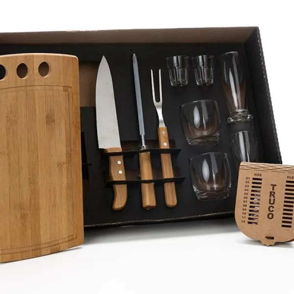 Kit para Churrasco, Drinks e Truco. Composto por tábua com três furos em Bambu; garfo em Bambu/Inox; faca 8; dois copos de Cerveja, dois copos de Whisky e dois copinhos de dose em vidro; caixa para truco com jogo de cartas, marcador de tentos e jogos em MDF. Como cortesia, na faca 8 fazemos uma gravação com os cortes do boi.